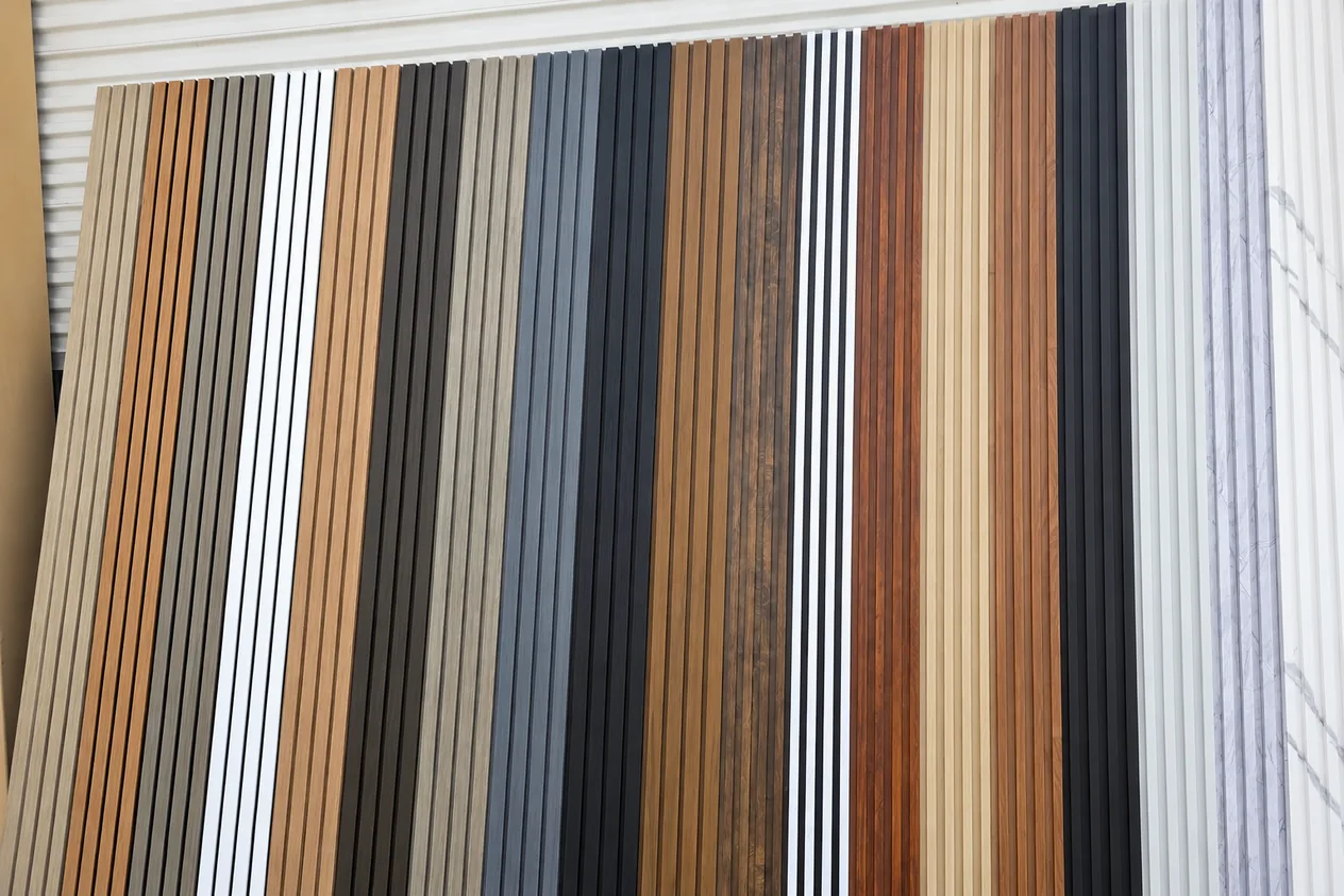 A wall of fluted WPC slat panel samples in oak, walnut, grey, white and black