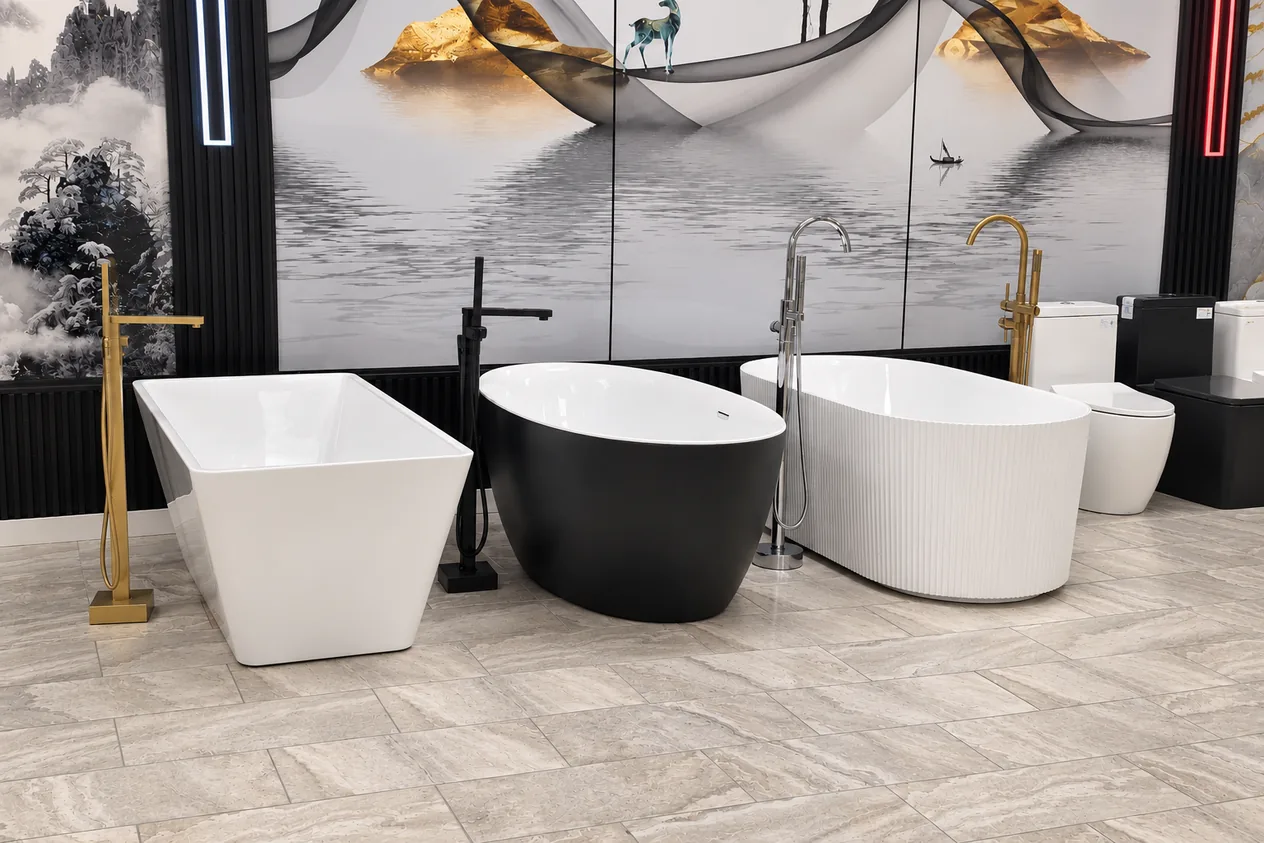 Three freestanding bathtubs — white square, matte black oval and white fluted — with gold and black floor-mounted tub fillers
